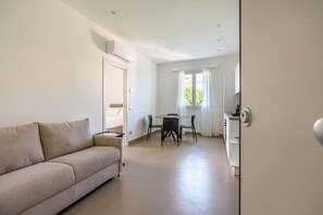 A modern living room with a sofa, a dining table with chairs, a kitchen area, and a window with curtains. - Crispi Terrace by Wonderful Italy (Palermo)