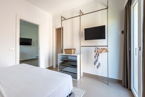 A modern hotel room with a bed, a TV, a wardrobe, and a sliding door. - Crispi Terrace by Wonderful Italy (Palermo)