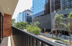 A modern building with a balcony, a street with pedestrians, and other buildings in the background. - w Sunny 1BR w Balcony in Vibrant San Isidro (Lima)