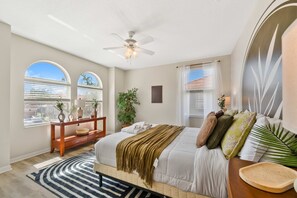 A bedroom with a bed, a ceiling fan, a window with blinds, a bedside table, and a nightstand. - Spacious 6BR home w/ pool & BBQ grill (Kissimmee)