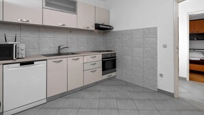 Een moderne keuken met witte kastjes, een magnetron, een spoelbak en een oven.