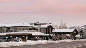 Un hotel con una zona salotto esterna coperta, un cartello che indica 'Peaks Hotel' e un paesaggio innevato sullo sfondo.