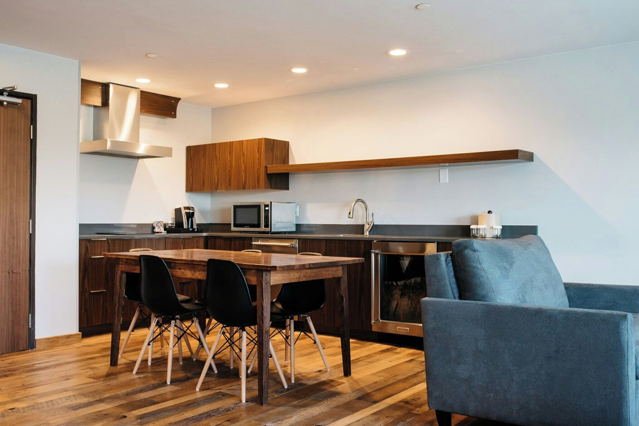 A modern kitchen with a wooden dining table and chairs, a built-in microwave, and a large stove.