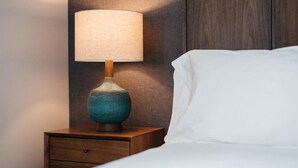 A bed with a white pillow, a wooden nightstand with a lamp, and a wall panel. - Park City Peaks (Park City)