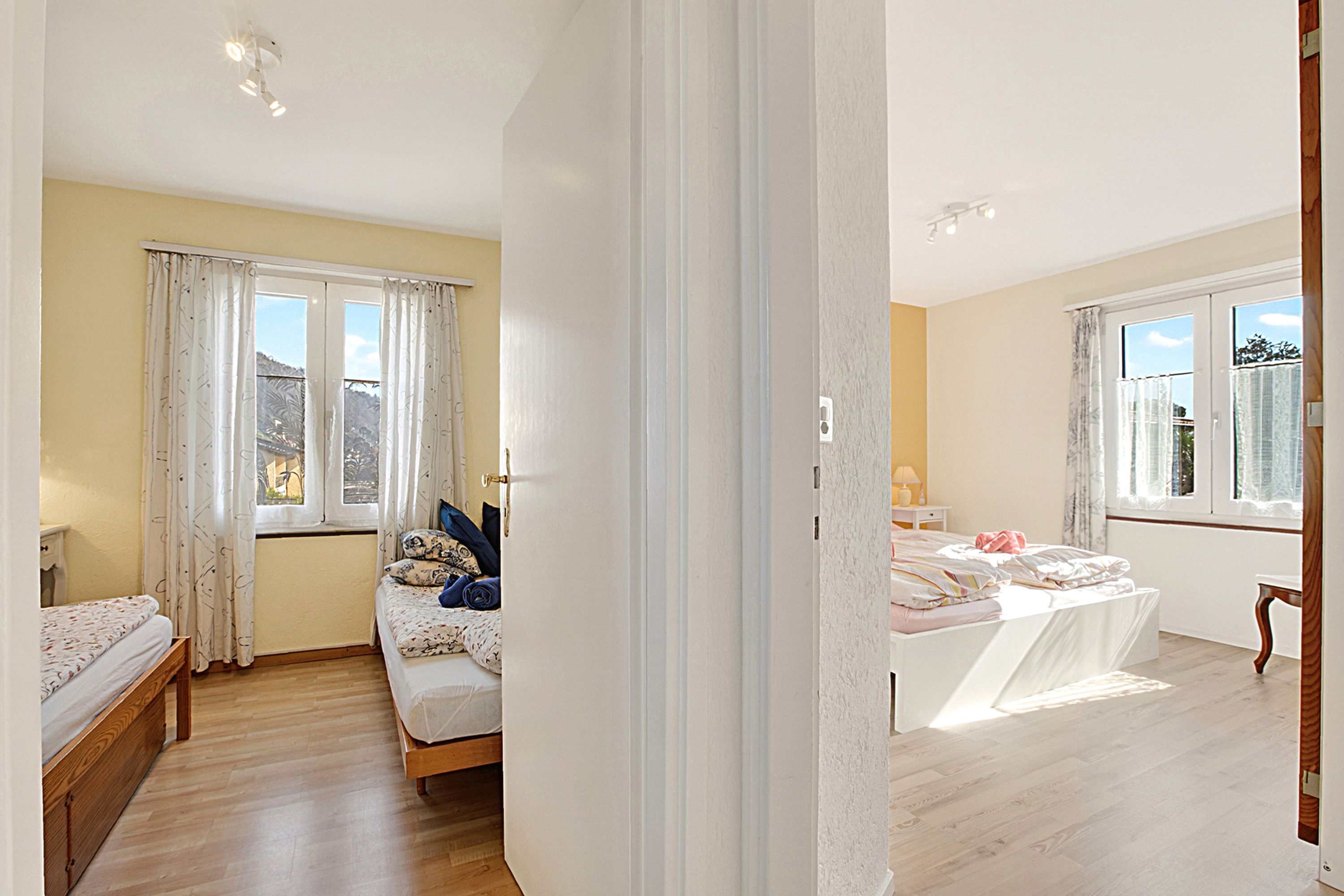 A bedroom with two beds, a window, and a door.