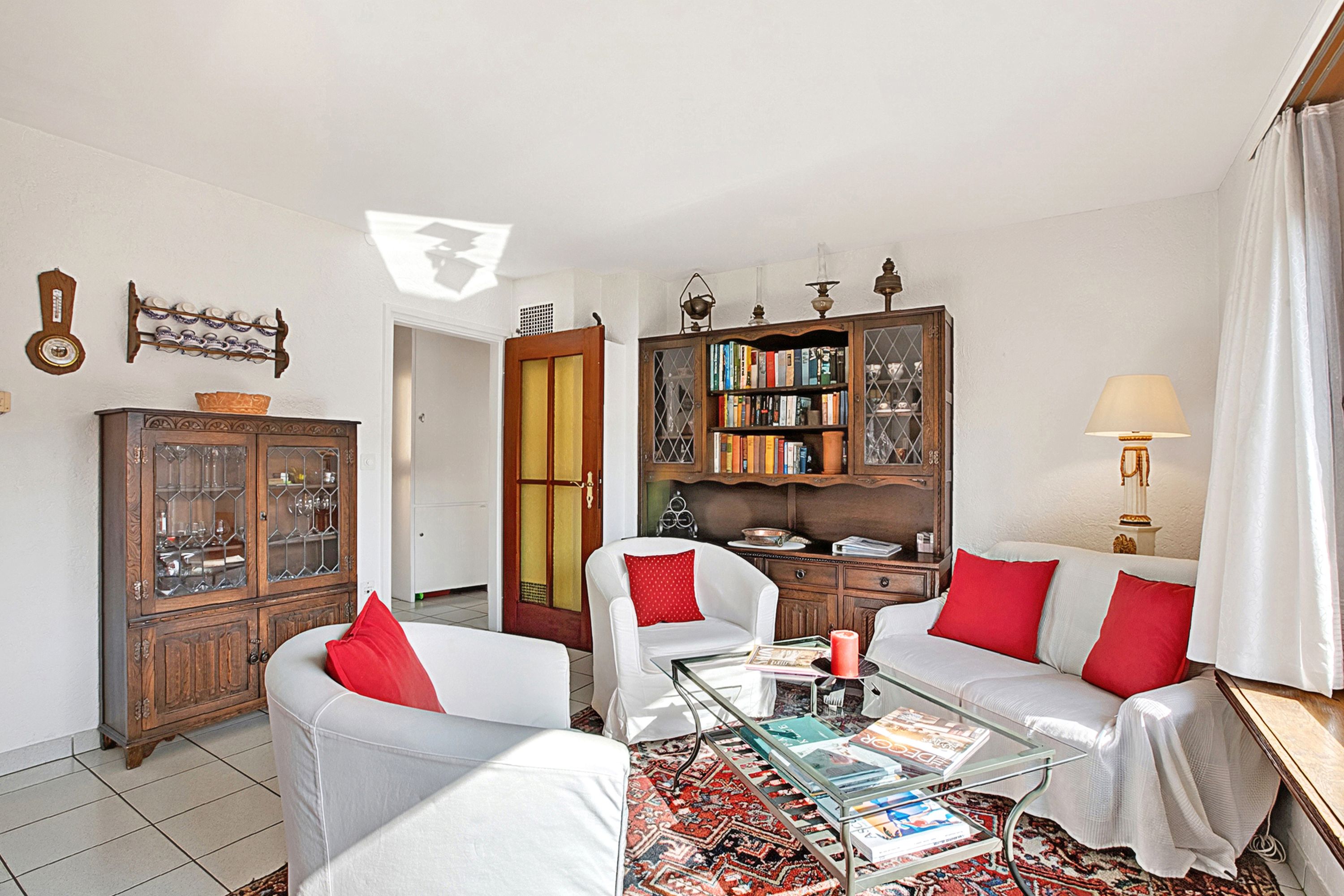 Una sala de estar con un sofá, sillones, una mesa de centro, una estantería y un aparador.