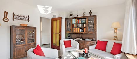 A living room with a sofa, armchairs, a coffee table, a bookshelf, and a cabinet.