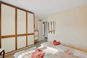 A bedroom with a bed, a wardrobe, a mirror, and a door leading to another room. - Casa Viola Losone for 8 (Losone)