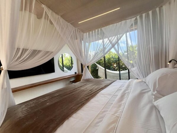 Une chambre à coucher avec un lit, un banc en bois et des rideaux en voile.