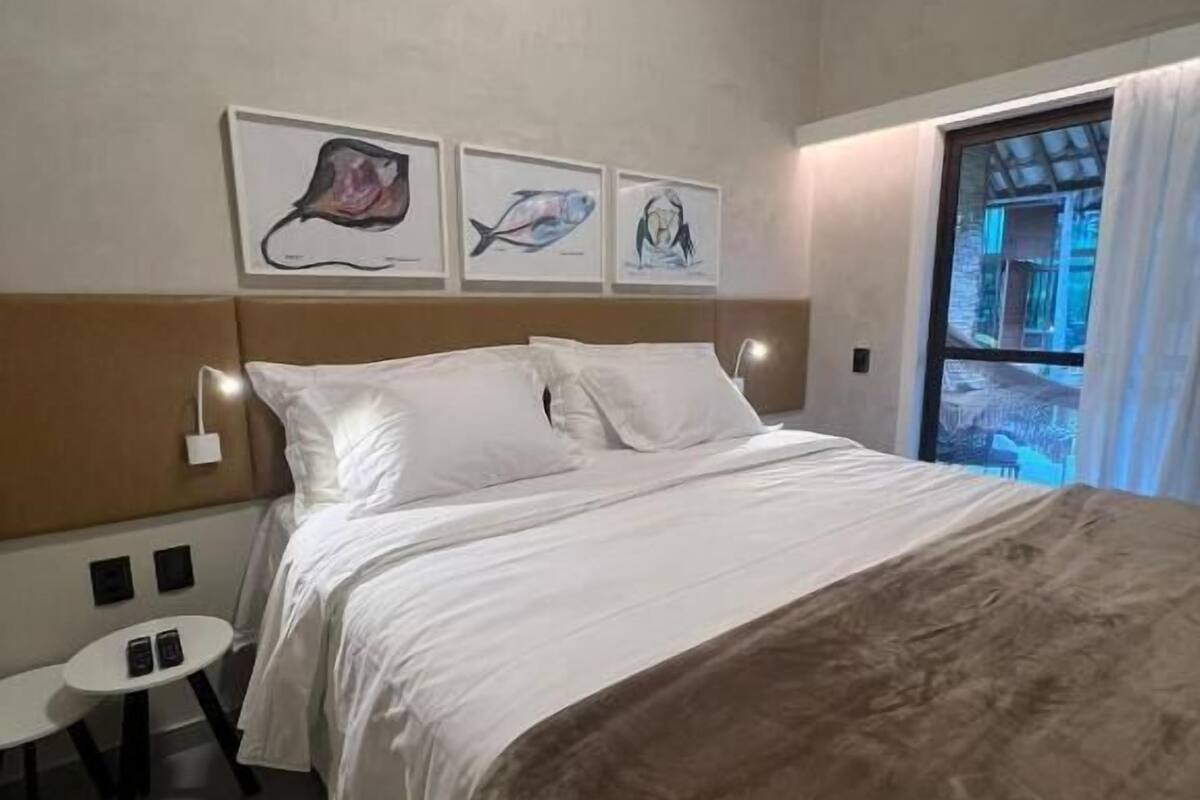 Habitación de hotel con cama, una mesita y una obra de arte en la pared.