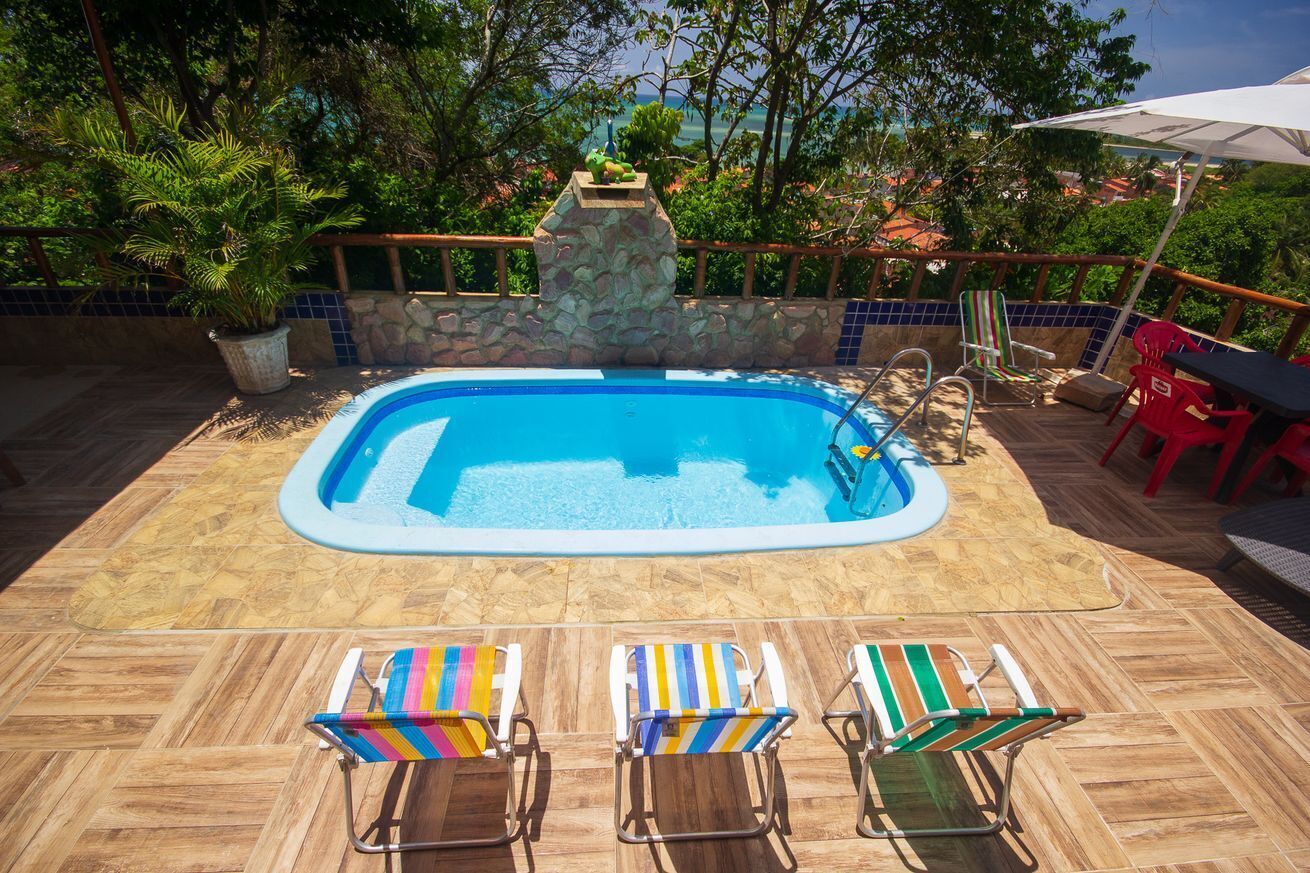 Ein Schwimmbecken mit einer Steinmauer, umgeben von Topfpflanzen und einer gefliesten Terrasse.