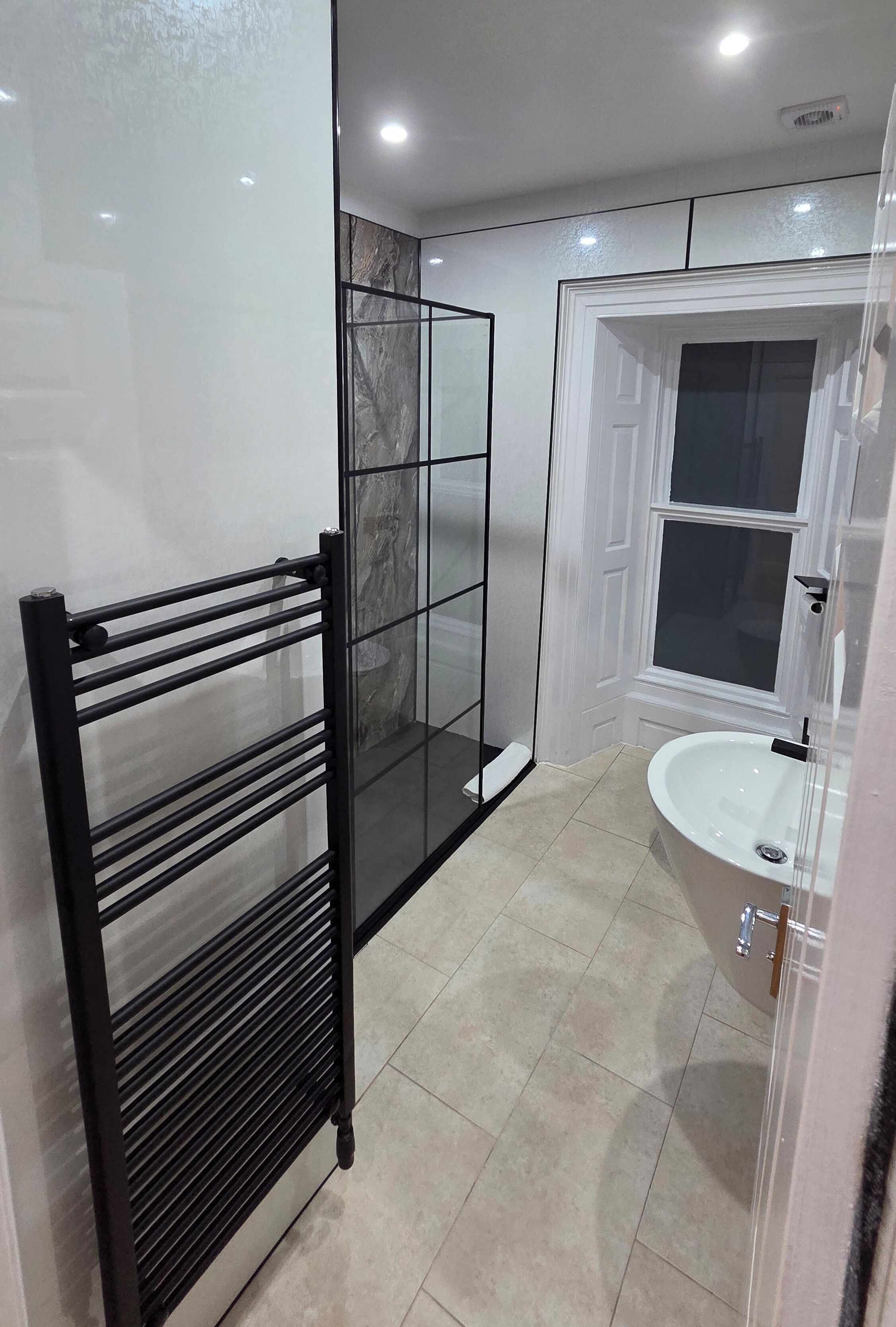 A bathroom with a glass shower enclosure, a white bathtub, and a white sink.