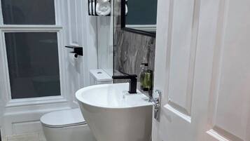 Een moderne badkamer met toilet, wastafel en een handdoekrek met handdoeken.