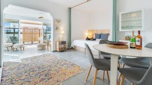 Ett modernt hotellrum med en säng, ett matbord, stolar, en takfläkt, ett stort fönster och utsikt över omgivningarna.