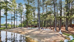 A campground with white lounge chairs, a wooden deck, and a pond. - Johnny`s Lucky 13 at Island Pointe (Wisconsin Dells)
