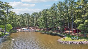 A lakeside resort with cabins, a dock, and a grassy area with chairs. - Johnny`s Lucky 13 at Island Pointe (Wisconsin Dells)