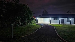 A modern building with a paved driveway leading to a garage, surrounded by greenery. - Charming 2-bedroom villa with AC in peaceful  de La Fortuna, San Carlos (San Carlos)
