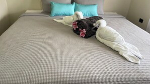 A bed with a textured grey bedspread, two pillows in shades of grey and blue, and two towels shaped like swans with pink flowers. - Charming 2-bedroom villa with AC in peaceful  de La Fortuna, San Carlos (San Carlos)