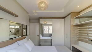 A hotel room with a bed, a large mirror, a wardrobe, and a chandelier. - Fully Equipped Apartments in the Condo With Pool in Canasvieiras - RPC (Florianópolis)