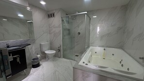 Et moderne badeværelse med en glasafskærmet brusekabine, badekar, toilet og en vask med spejl.