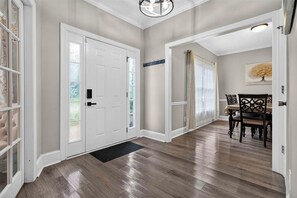 A hallway with a wooden floor, white doors, and a dining area with a table and chairs. - Fabulous 4BR Home, Office, Game Room & Deck/Huge Lawn (Conyers)