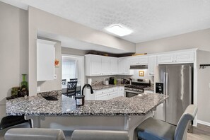 A modern kitchen with white cabinetry, granite countertops, and stainless steel appliances. - Fabulous 4BR Home, Office, Game Room & Deck/Huge Lawn (Conyers)