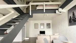 A modern interior with a staircase, a sofa, a TV, and framed artwork on the wall. - Duplex apartment in the center of Metz (Metz)