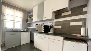 A compact kitchen with white cabinets, a microwave, a coffee machine, and a dishwasher. - Duplex apartment in the center of Metz (Metz)