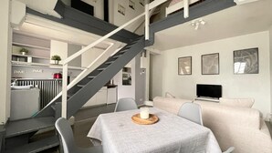 A modern interior with a staircase, a dining area, and a living space with a TV. - Duplex apartment in the center of Metz (Metz)