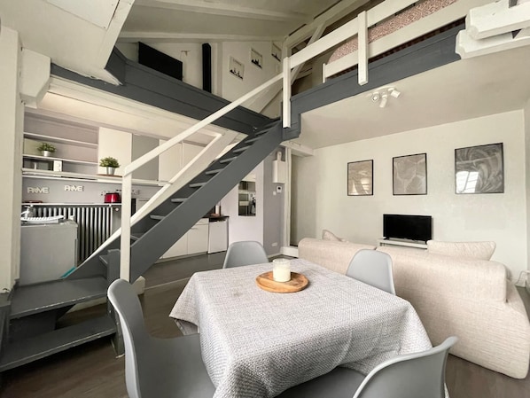 Ein modernes Interieur mit einer Treppe, einem Essbereich und einem Wohnbereich mit Fernseher.