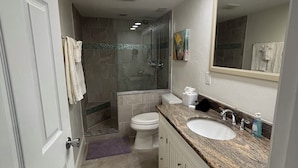 Une salle de bain équipée d’une douche, de toilettes, d’un lavabo et d’un grand miroir.