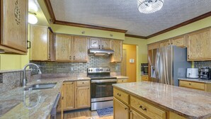 Eine Küche mit Holzausstattung, einem Edelstahl-Kühlschrank, einem Doppelbackofen und einer Arbeitsplatte aus Granit.