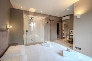 A modern hotel room with a large bed, a marble shower enclosure, a vanity with a mirror, and a small round table. - Interno 5 - [Parcheggio gratuito] (Alba)