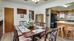 A dining area with a wooden table, chairs, a ceiling fan, and a kitchen in the background. - 2-Acre Farmhouse w/ Animals! Allendale Retreat (Allendale)
