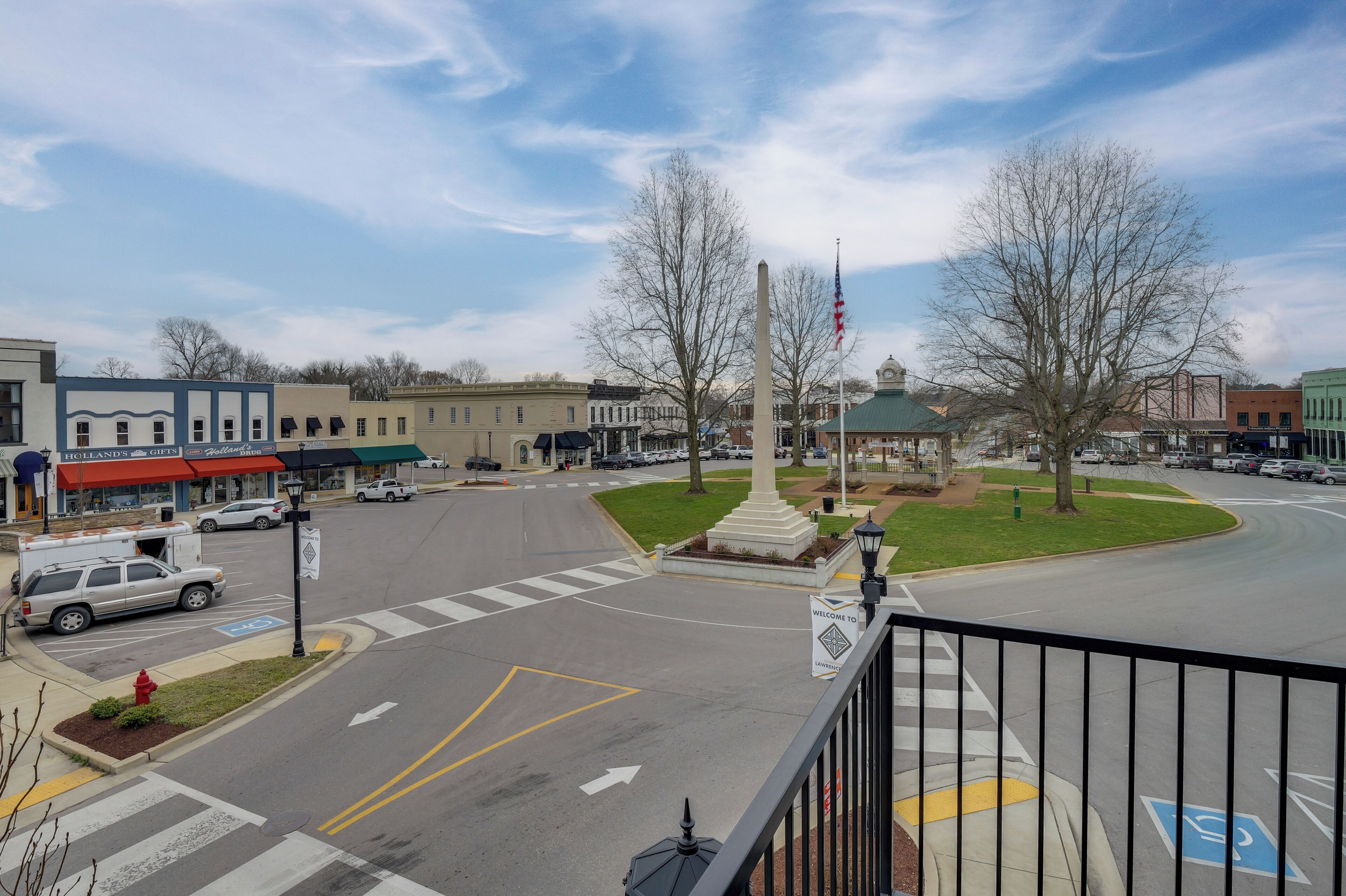 A street view with a monument, a flag, and a 'Welcome to' sign.
