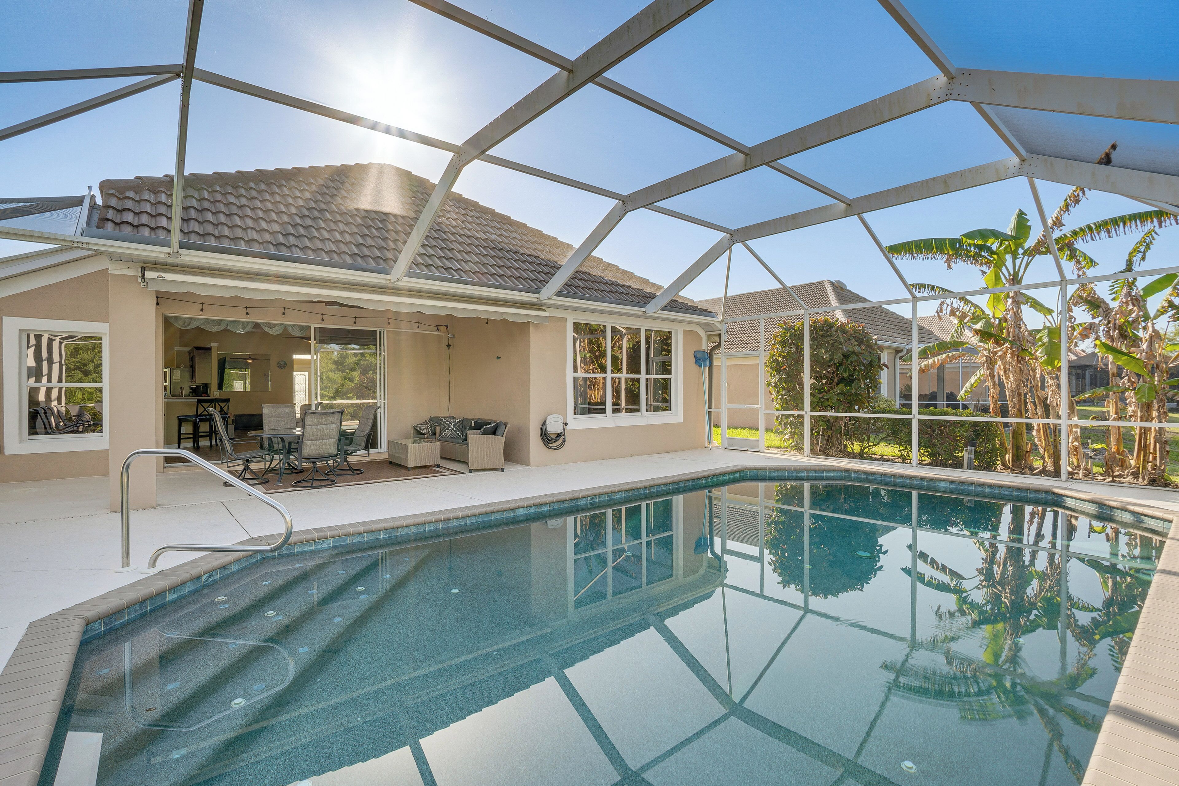 Une piscine entourée de parois en verre, un espace patio aménagé avec du mobilier d’extérieur et une vue sur le paysage environnant.