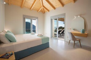 A bedroom with a large bed, a desk, a chair, a mirror, and a view of the outdoors. - Ponti Monti - Two Bedroom Villa, Sleeps 4 (Vasiliki)