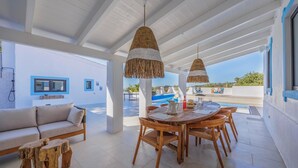 A spacious patio with a dining table, chairs, and a sofa. A pool is visible in the background. - Vista Azul - Five Bedroom Villa, Sleeps 10 (Loulé)