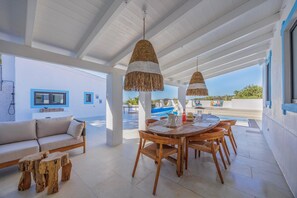 A spacious patio with a dining table, chairs, and a sofa. A pool is visible in the background. - Vista Azul - Five Bedroom Villa, Sleeps 10 (Loulé)