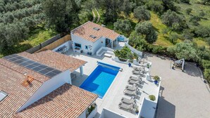 A modern villa with a swimming pool, solar panels, and a view of the surrounding countryside. - Vista Azul - Five Bedroom Villa, Sleeps 10 (Loulé)