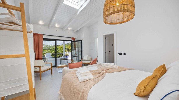 A bedroom with a bed, a balcony with chairs, a wooden ladder, and a hanging light fixture. - Vista Azul - Five Bedroom Villa, Sleeps 10 (Loulé)