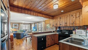 A spacious kitchen with wooden cabinets, a central island, and a stainless steel sink. - Turtle Bay Cottage- 4BR Home- Ping Pong, Corn Hole (North Myrtle Beach)