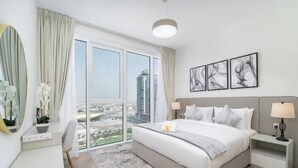 A hotel room with a bed, bedside tables, a mirror, and a view of the city. - Vogue | Al Wasl 1 Residence near World Trade Centre (Dubai)