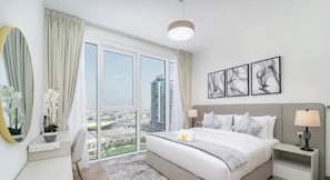 Una habitación de hotel moderna con una cama grande, un escritorio, una silla y vistas a la ciudad.