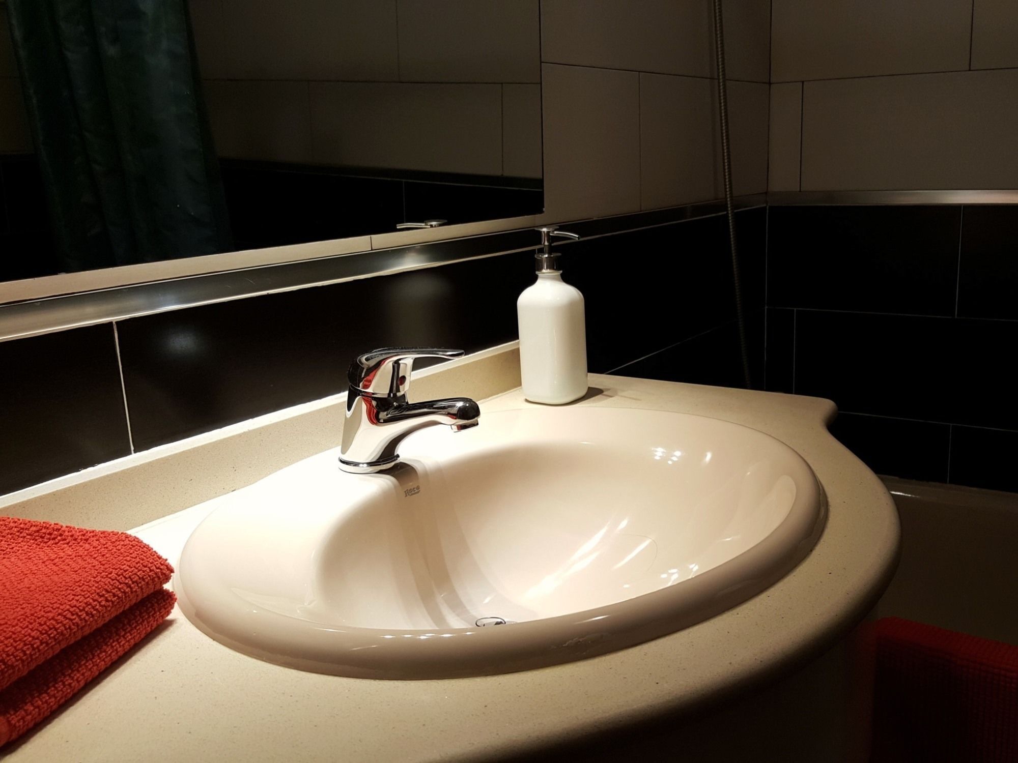 Ein Waschtisch mit Spiegel, Wasserhahn und Seifenspender.