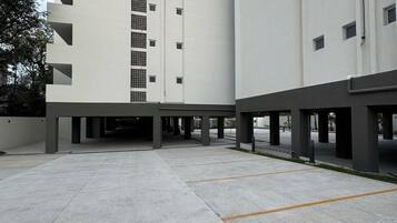 A modern building with a flat facade, multiple floors, and a covered parking area.