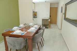 A dining area with a long table set for four, chairs, a kitchen area with cabinets, and a door leading to another room. - Depto. 2 rec. en Playa Mocambo (Boca del Río)