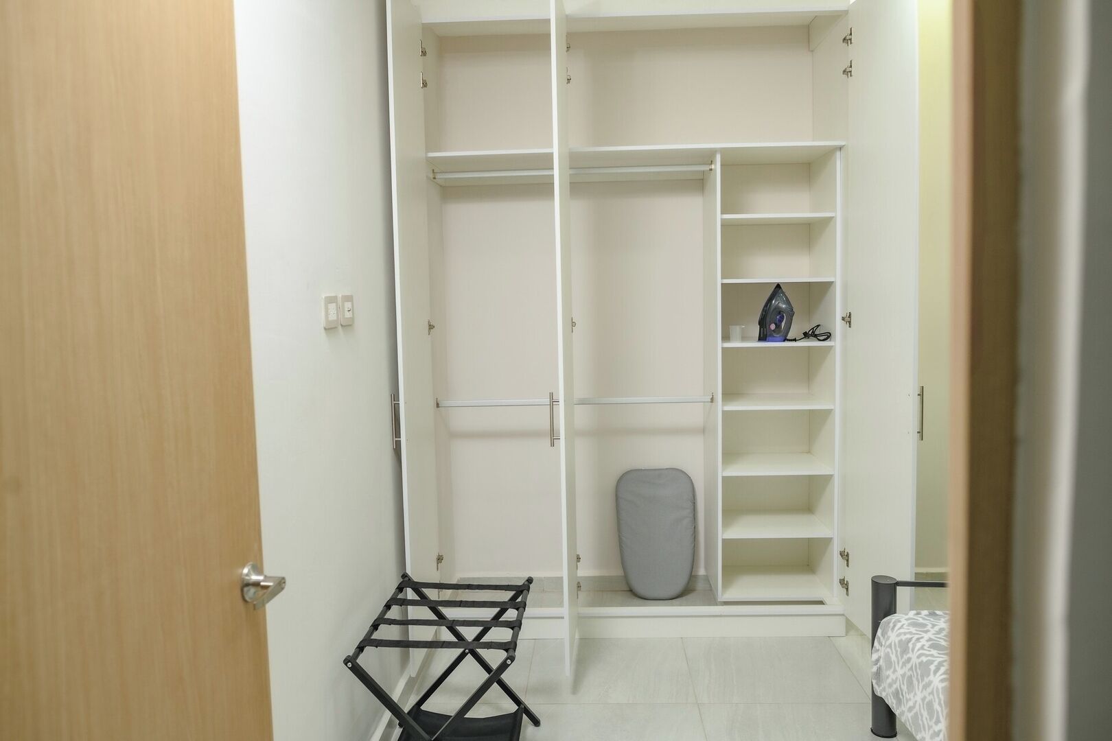 Ein begehbarer Kleiderschrank mit offenen Türen, Regalen und einer Kleiderstange.
