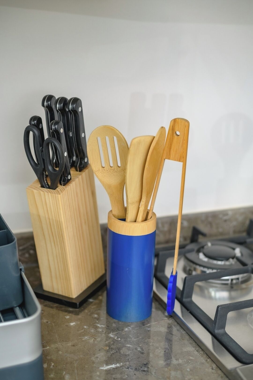 A kitchen counter with a knife block, a blue utensil holder, and a gas stove.