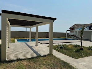 A covered outdoor area with a swimming pool, a small garden, and a building with a thatched roof. - Depto. 2 rec. frente al Mar (Bahia) (Boca del Río)